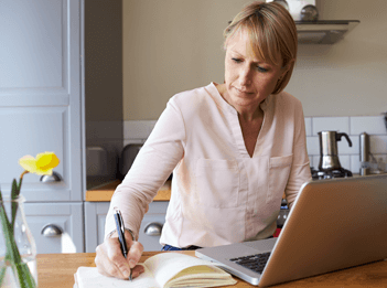 image showing lady working from home on a laptop in her kitchen.