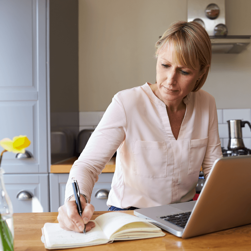 image showing lady working from home on a laptop in her kitchen.